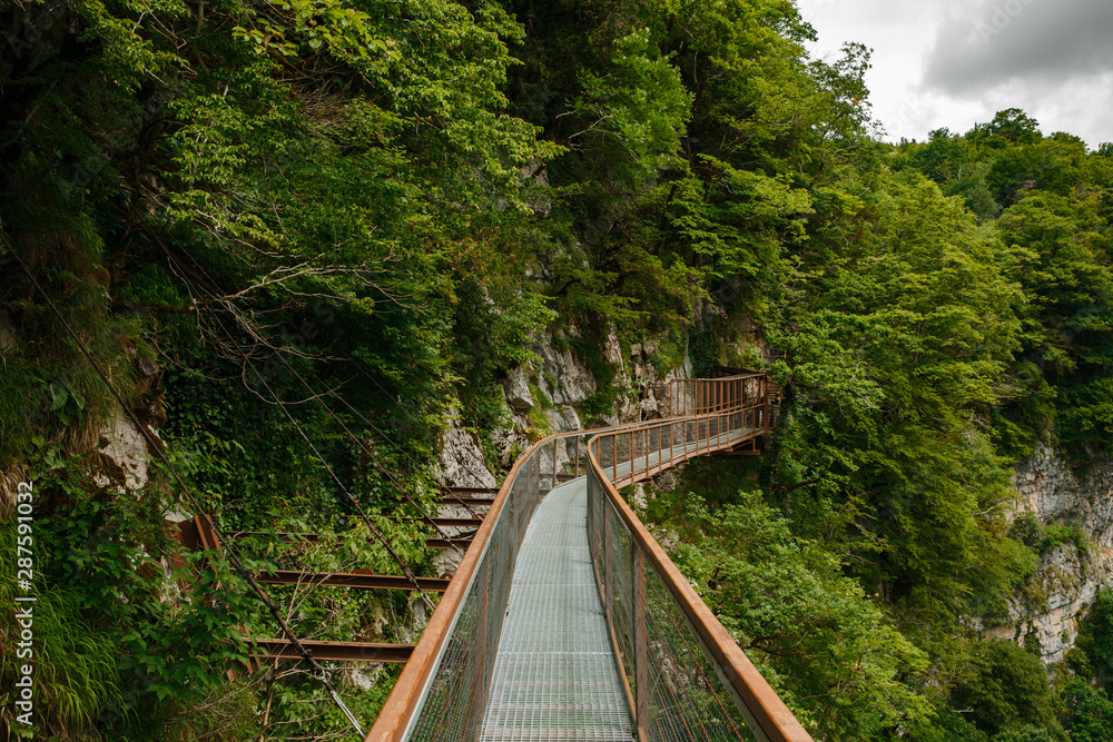 Okatse Canyon in Georgia. Waterfall on the cliffs of the reserve. Beautiful natural canyon, hiking trail over the canyon, overlooking the mountain river, near Kutaisi. Okatse Canyon in Georgia. Waterfall on the cliffs of the reserve. Beautiful natural canyon, hiking trail over the canyon, overlooking the mountain river, near Kutaisi.