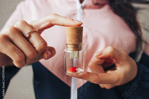 A glass flash drive in the form of a bottle in the hands woomen photo