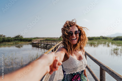 travel nature follow me woman in a natural park holding hand of boyfriend following leading girlfriend walking. Tourism, love and travel concept © Eva