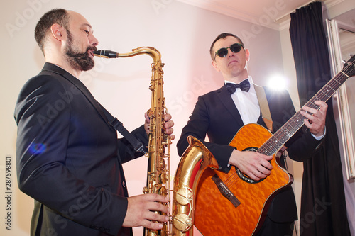 Photography Group of two musicians, male jazz band, guitarist and saxophonist in classical c