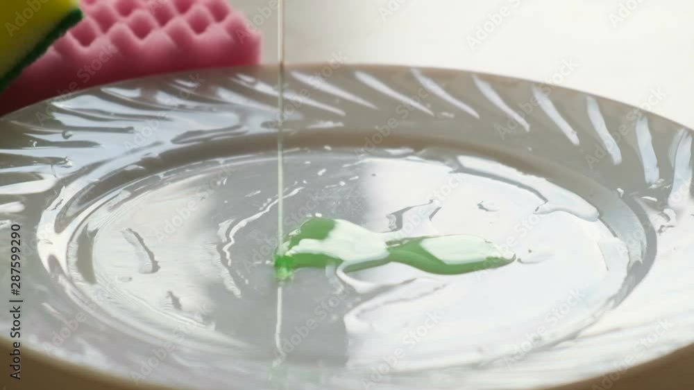 Dishwashing gel is poured on a plate, close up Dishwashing gel is poured on a plate, close up