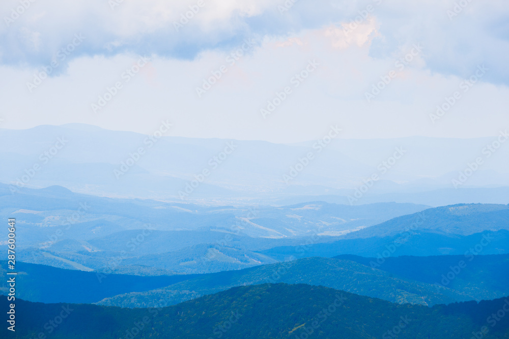 Landscape with blue silhouettes of hills and mountains with blue sky.
