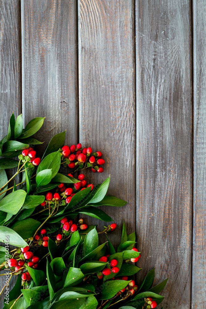 Green leaves and red berries frame on wooden background top view copyspace Green leaves and red berries frame on wooden background top view copyspace