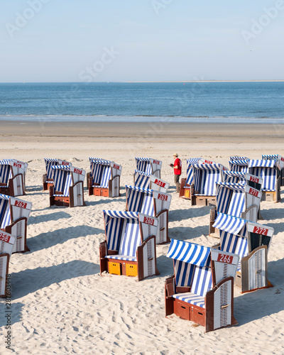 Photos man in red shirt checks beach korbs on the island of norderney in germany on sun