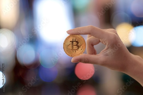 Girl holding golden bitcoin on bokeh background