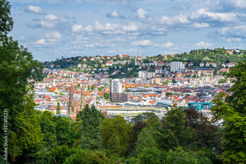 Germany, Downtown stuttgart houses and churches seen from above green tree tops near karlshoehe in summer surrounded by trees and nature landscape