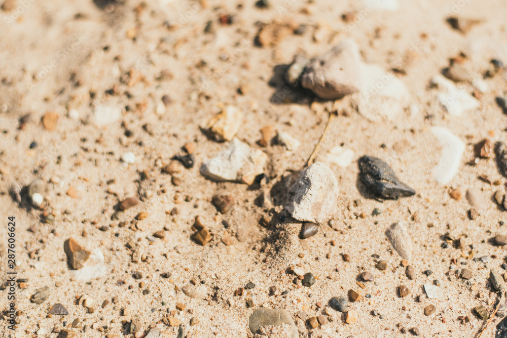 Sand and smooth stones on the beach. Sandy texture, coast, river bank. Large sand with small stones, bright sunlight. The concept of leisure, summer, beach. Sand and smooth stones on the beach. Sandy texture, coast, river bank. Large sand with small stones, bright sunlight. The concept of leisure, summer, beach.