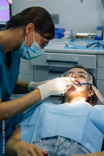 Εκτύπωση καμβά process of placing white dental braces to a Caucasian girl in a dental clinic wi
