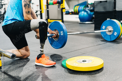 Disabled athlete with leg prosthesis training at the gym. Paralympic Sport Concept.