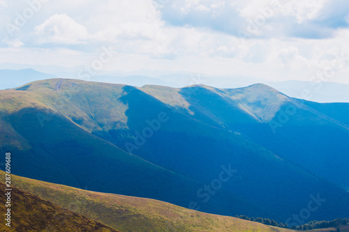 Landscape of Carpathian Mountains with blue silhouettes of hills and mountains with blue sky.