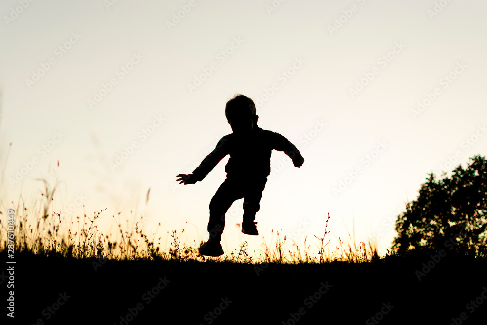 Silhouete of small boy running on top of the hill