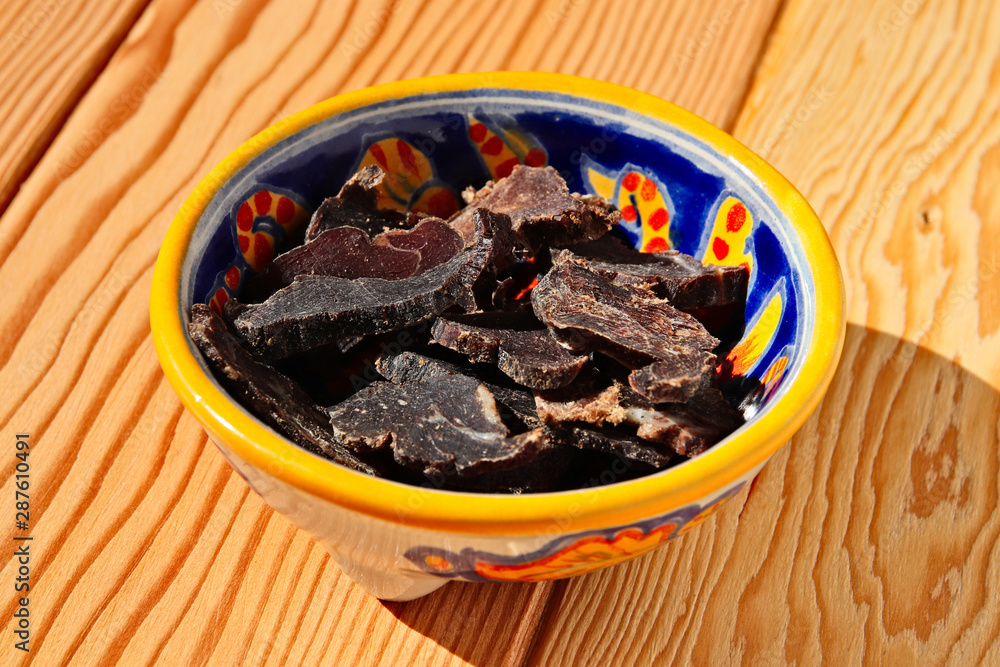 Biltong (dried meat) on a wooden board, this is a traditional food snack that can be found in South Africa. Biltong (dried meat) on a wooden board, this is a traditional food snack that can be found in South Africa.