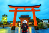 Woman traveler with backpack at fushimi inari taisha shrine in Kyoto, Japan.