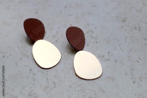 Trendy gold earrings on marble background. Selective focus.