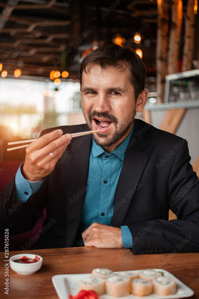 A man in costume eats sushi in a restaurant