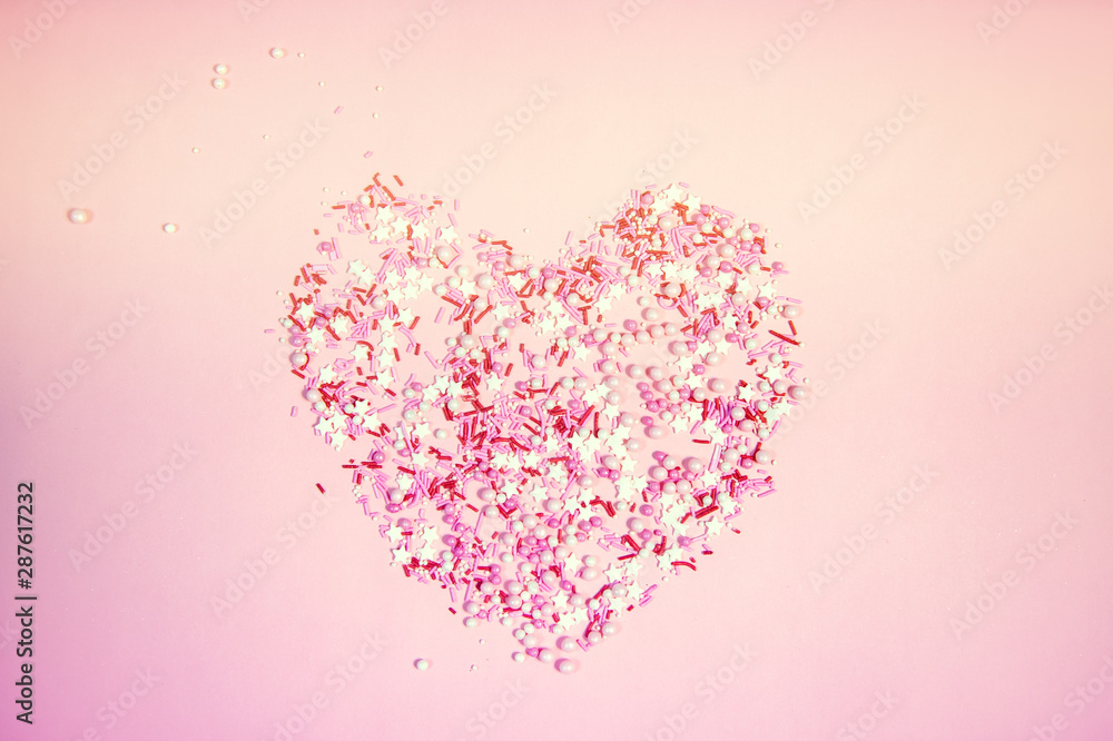 Colorful sprinkles on a pink background, top view with copy space
