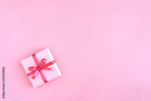 Gift box with ribbon and bow on color background and space for text. Top view 