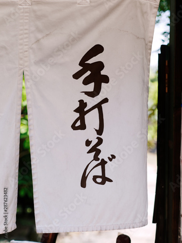 Traditional white Noren hanging at the entrane of the Japanese Soba noodle restaurant. The texts mean: Handmade Soba noodle. photo