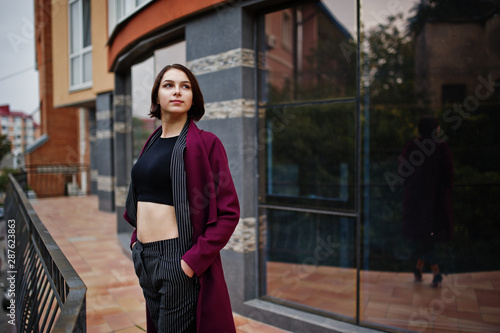 A tall leggy young beautiful and elegant model woman at claret coat.