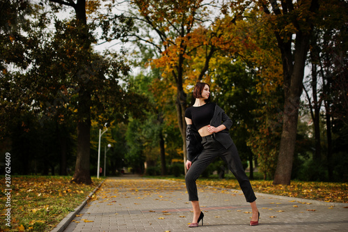 Fototapeta Naklejka Na Ścianę i Meble -  A tall leggy young beautiful and elegant model woman at formal wear posed at autumn background.