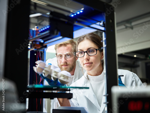 Two technicians looking at turbine wheel being printed in d printer photo