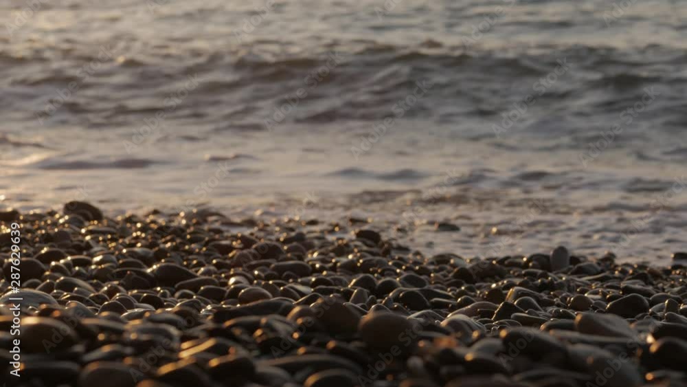 The sun rises over the sea at dawn. Sea surf and pebbles in the morning sun. The sun rises over the sea at dawn. Sea surf and pebbles in the morning sun.