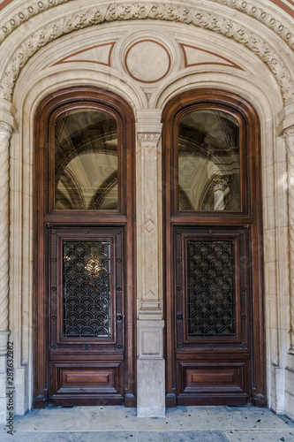 Wooden brown Front Door of a Luxurious house. Doors with glass and forged window grille © Konstantin