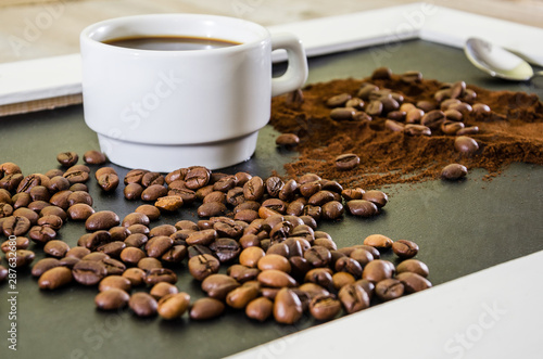 cup of coffee, ground coffee and coffee beans on a black background.