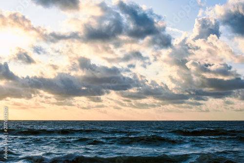 The ocean, rough sea water with horizon and clouds during evening sunset