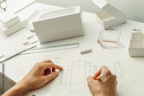 The designer draws a sketch for cardboard packaging. Create eco-friendly paper boxes.  photo