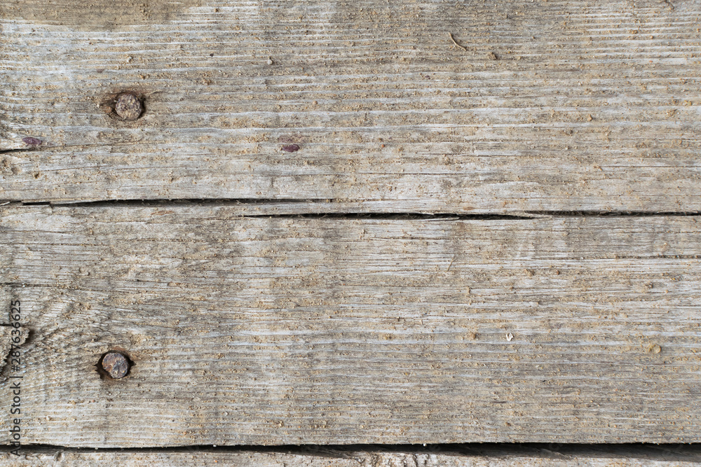 Old gray-brown natural wood background in the form of a board with cracks, knots and a rough surface Old gray-brown natural wood background in the form of a board with cracks, knots and a rough surface