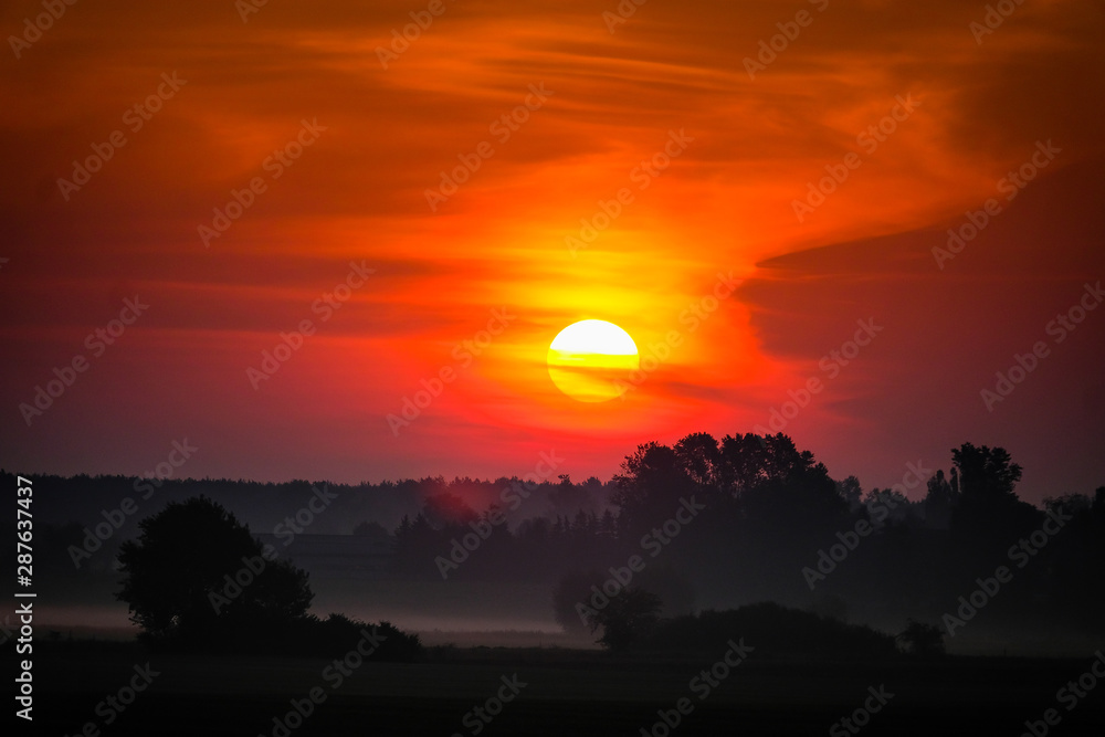 Autumn sunrise or sunset in the fog with forests in the background