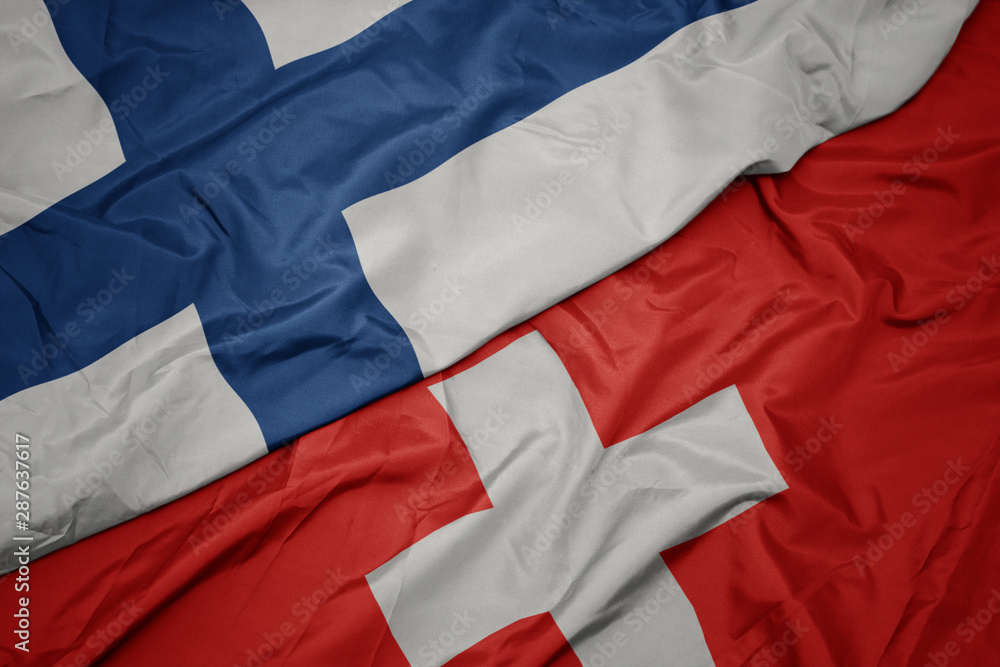 waving colorful flag of switzerland and national flag of finland. waving colorful flag of switzerland and national flag of finland.