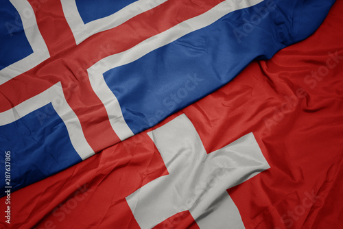 waving colorful flag of switzerland and national flag of iceland.