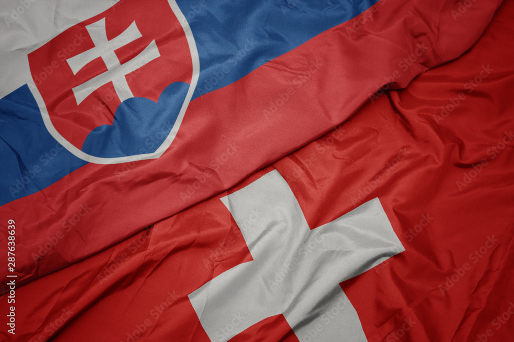 Fototapeta premium waving colorful flag of switzerland and national flag of slovakia.