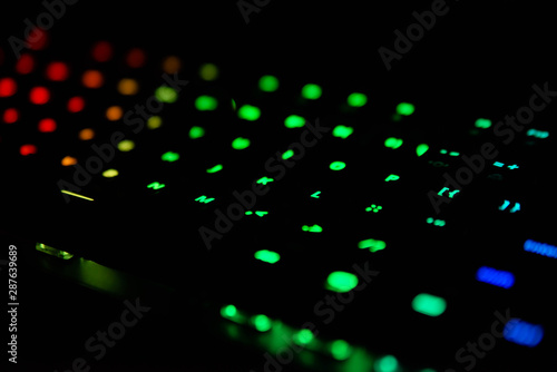 Diagonal RGB gaming keyboard bokeh background. Colorful mechanical keyboard in dark room. Gaming and technology concept