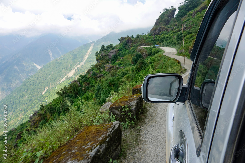 POV: Driving along the edge of scary bumpy road overlooking the forest in Nepal.