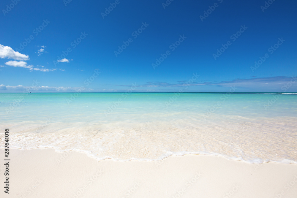 The edge of the wave on the white sand. Clear blue sky and turquoise water. Paradise on earth, the beauty and tranquility of nature. The best beaches in the world