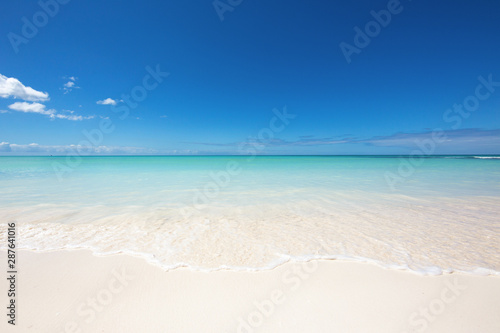 The edge of the wave on the white sand. Clear blue sky and turquoise water. Paradise on earth, the beauty and tranquility of nature. The best beaches in the world