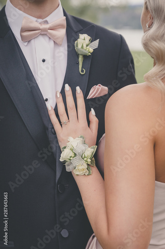 Photo A couple dressed fancy for a special occasion showing their corsage and boutonni