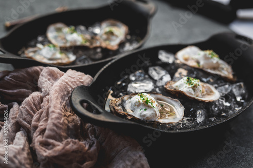 Raw oyster with mignonette sauce, celery & cream in cast iron on ice photo