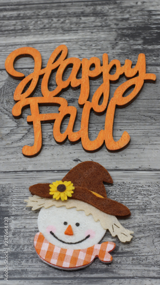happy fall text, greeting card, fall image with happy scarecrow face laying flat on a grey rustic wood background, vertical close up