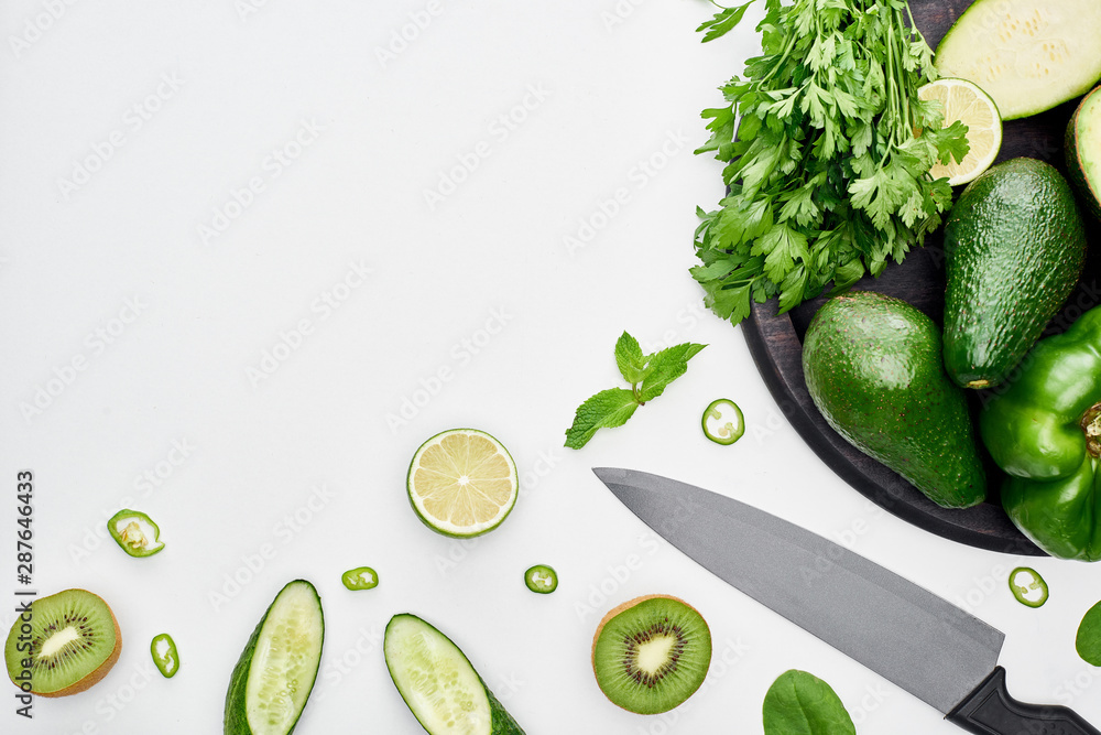 Φωτογραφία top view of knife, avocados, peppers, kiwi, limes and greenery on pizza skillet