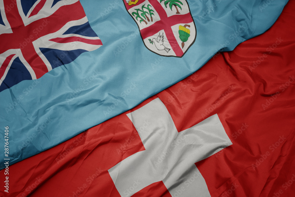 Fototapeta premium waving colorful flag of switzerland and national flag of Fiji .
