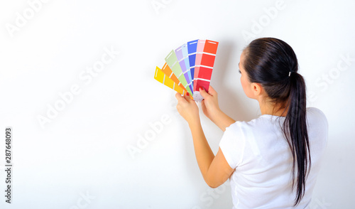 young girl holds a color palette in her hands and chooses a color for repairs in the house  on a white background