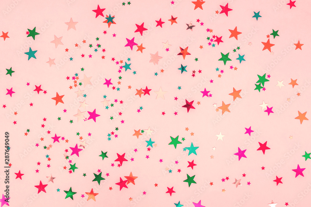 Abstract photo of multi-colored stars glitter on pink background. Festive holiday pastel backdrop. Celebration concept. Top view, flat lay. Horizontal Abstract photo of multi-colored stars glitter on pink background. Festive holiday pastel backdrop. Celebration concept. Top view, flat lay. Horizontal