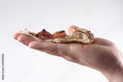 close up on the hand holding the slice of sliced pizza