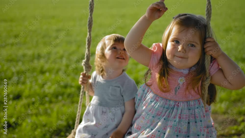 Faces of two girls swinging in a field on a rope swing close-up Faces of two girls swinging in a field on a rope swing close-up