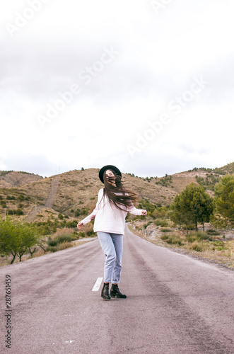 .happy woman with sombero dancing in the middle of an empty road in a rural area