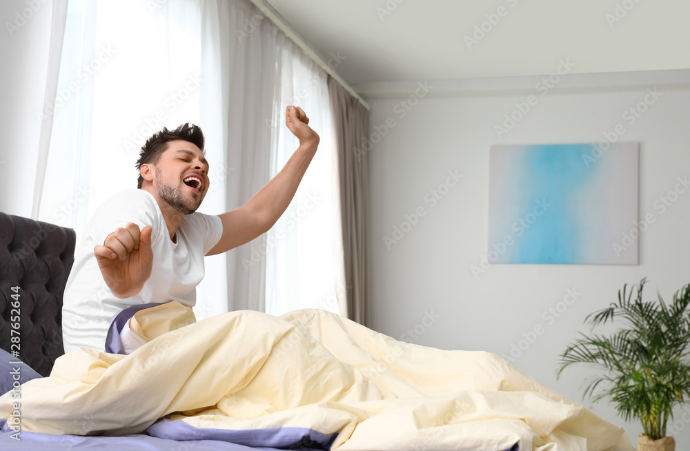 Handsome man stretching in morning, space for text. Bedtime Handsome man stretching in morning, space for text. Bedtime